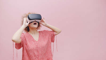 Girl wearing Virtual Reality goggles VR Box watching a 3D movie. Feeling amazed. The girl is lost in...