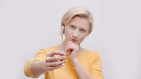 Girl holding a toothbrush pointing it towards the camera. Morning routine. The girl is dressed in a...