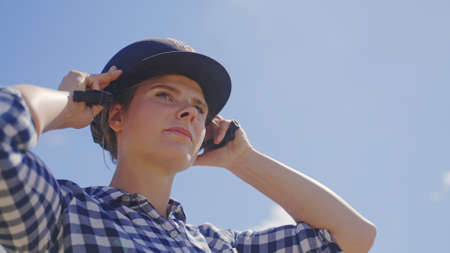 a young beautiful girl with a plaid shirt puts a helmet on her head. High-quality photo