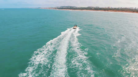 the speedboat turns on the water turns towards the shore and makes foam on the water and waves....