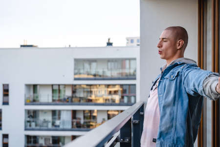 Caucasian bald gay man standing on a balcony and spreading his arms. High quality photoの写真素材