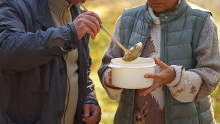 Two caucasian people sharing soup with each other. Helping people in need concept. High quality photoの写真素材