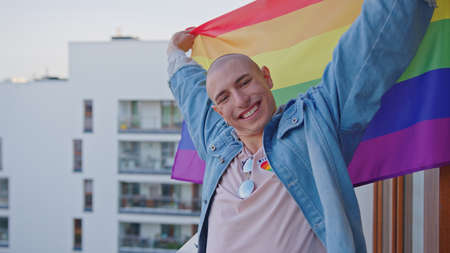 gender fluid person grinning at camera demonstrating pride rainbow flag and fighting for their...