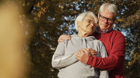 portrait of elderly Caucasian couple woman looking at her husband, man looking down covering his...