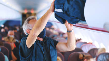 2021.08.18 Mallorca, Spain focus on an elderly man with a mask on his face who puts a travel bag in...