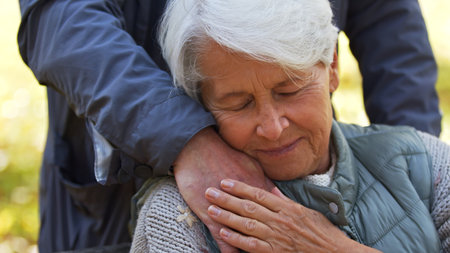 Portrait of elderly Caucasian lady leans to the hand of her husband, man stands behind his wife closing eyes emotional support concept . High quality photoの写真素材