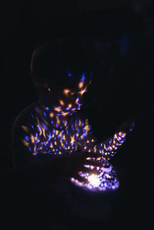 Night time before going to bed. Little boy playing with star projector. Vertical Shot. High quality photoの写真素材
