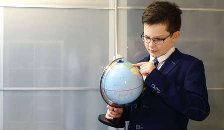 Schoolboy in glasses with a globe in his hands look at globe surface.の写真素材