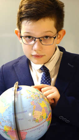 Schoolboy in glasses with a globe in his hands.の写真素材