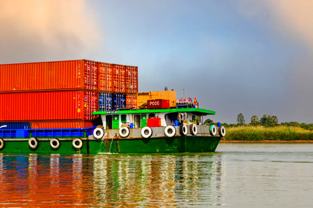 The colorful stern of a barge carrying red containers for delivery in Vietnam from Cambodia.のeditorial素材