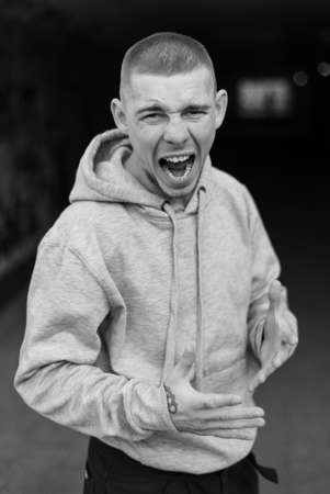 A bully guy in a light sports jacket with a hood. Black and white photo. BW