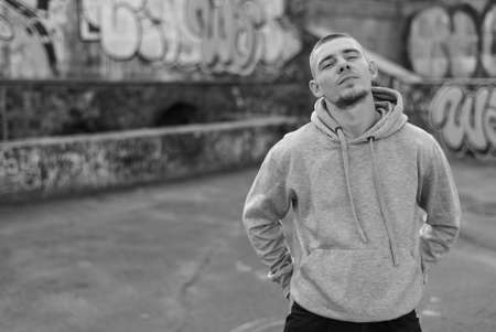 A bully guy in a light sports jacket with a hood. Black and white photo. BW