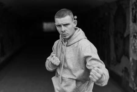A bully guy in a light sports jacket with a hood. Black and white photo. BW