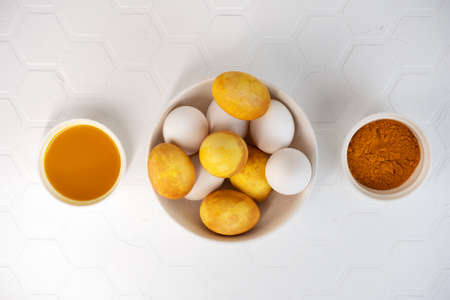 Yellow and white Easter eggs in a bowl. Natural coloring Easter eggs with turmeric powder in yellow color.の写真素材