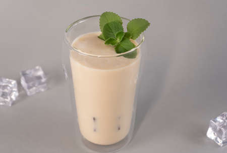 Glass of traditional Indian lassi drink with mango, mint and ice on a grey background.の写真素材