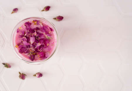 Pink rose milk with rose petals in a glass. Healthy drink moon milk. Top view. Copy space.の写真素材