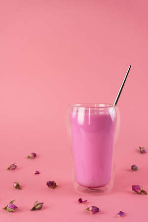 Pink rose milk with rose petals in a double walled glass. Healthy drink moon milk. Vertical orientation.の写真素材