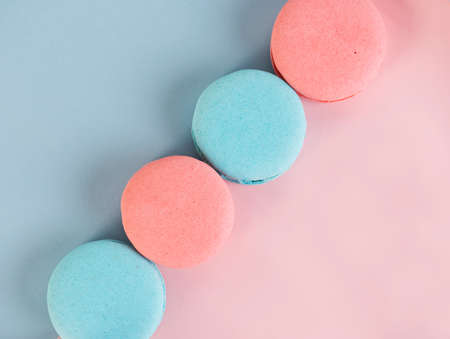 Delicious colorful french cookies macaroons on pink and blue background. Top view. Selective focus.の写真素材