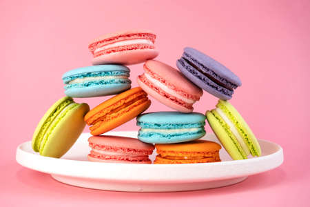 Delicious colorful french macaroons on white plate. Pink background.の写真素材