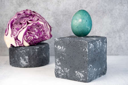 Blue Easter egg on grey podium or pedestal. Natural coloring Easter eggs with red cabbage. Easter egg design. Selective focus.の写真素材