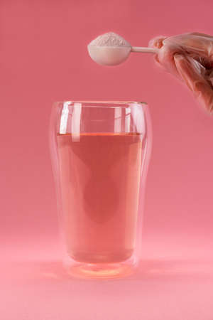 Adding collagen powder in a glass of water. Superfood additives. Vertical.の写真素材