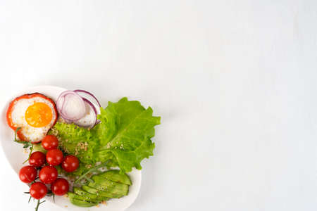 Healthy breakfast in the morning with fried egg and vegetables on white plate. Copy space. Top view.の写真素材