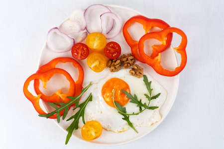 Healthy breakfast in the morning with fried egg and vegetables on white plate. Top view.の写真素材