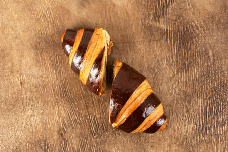 Fresh french chocolate croissant cut in half. Wooden background. Breakfast concept.の写真素材