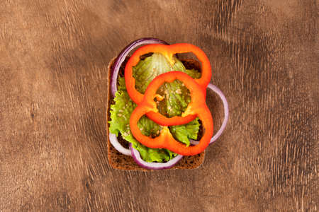 Sandwich or toast on the wooden background. Toast with onion rings, bell peppers and green salad. Vegetarian and vegan food.の写真素材