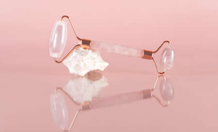 Gouache quartz roller for the face massage. Anti-aging and lifting for healthy and youthful skin. Home facial skin care. Organic facial cosmetics on a pink background. Spa treatments.の写真素材