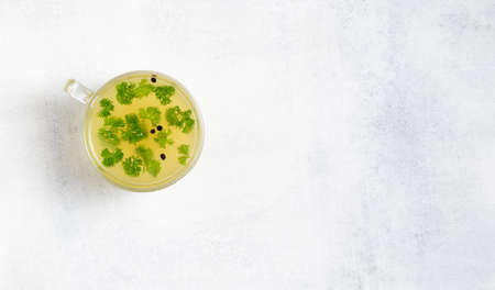 Cup of homemade turkey bone broth on white background with parsley, peppercorns.の写真素材