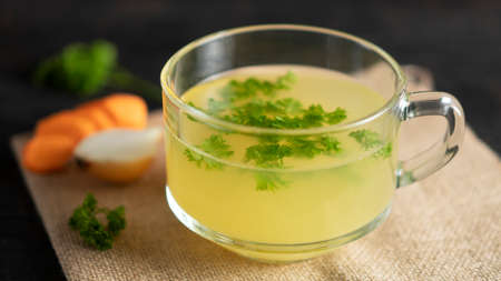 Homemade chicken Bone Broth in cup with ingredients, bones contain collagen.の写真素材