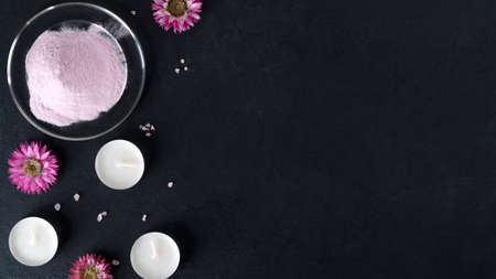 Natural collagen protein powder for skin regeneration. Hydrolyzed food additives. Healthy and anti age concept. Collagen powder with flowers and candles on dark background. Top view. Copy space.の写真素材