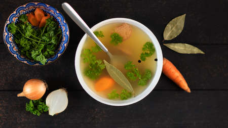 Warm homemade chicken broth in white bowl with ingredients. Collagen for joints.の写真素材