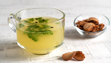 Homemade beef bone broth in glass cup with parsley leaves, peppercorns, croutonsの写真素材