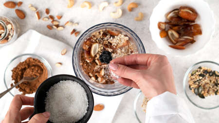 Step by step cooking Energy balls. Step 4 recipe of no bake energy balls. Adding coconut flakes and other ingredients to the blender or food processor. Healthy raw dessert, vegetarian candies.の写真素材