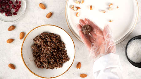 Step by step cooking Energy balls. Step 8 recipe of no bake energy balls. Making round balls from the mixture of nuts, dates, cocoa powder, coconut flakes, oats and dried cranberry. Healthy eating.の写真素材