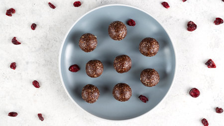 Energy balls on a blue plate. Homemade healthy raw vegan dessert of nuts, dates, peanut butter, cocoa powder, coconut flakes, oats and dried cranberries. Healthy eating. Fitness snack. Selective focusの写真素材