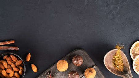 Energy balls with cinnamon sticks, anise, orange slices and almond on dark wooden cutting board. No...