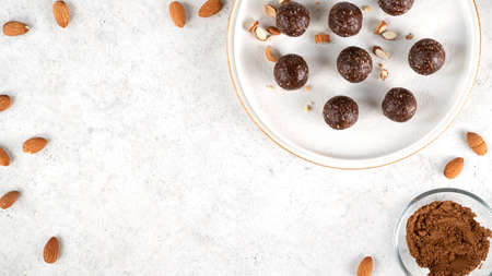 No bake energy balls. Homemade healthy raw vegetarian dessert of nuts, dates, peanut butter, cocoa powder, coconut flakes, oats is ready to eat. Healthy eating. Selective focus. Top view. Copy space.の写真素材