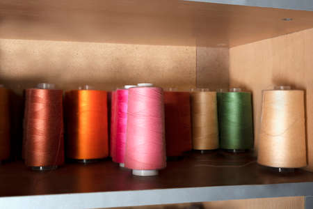 Close-up of multicolored spools of thread for the industrial sewing machine. Selective focus.