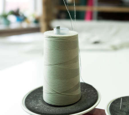 Close-up of a spool of thread on the industrial sewing machine. A seamstress workplace with a spool...