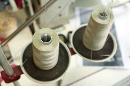 Close-up of a two spools of thread on the industrial sewing machine. A seamstress workplace with a...
