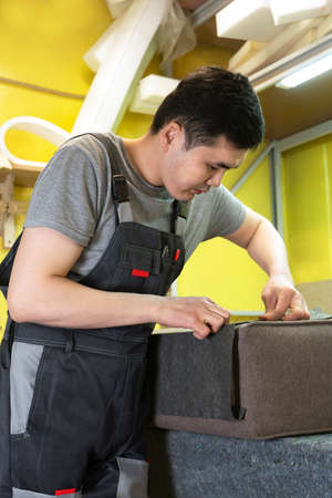 Furniture upholstery. A carpenter fixes the fabric. Vertical orientation.の写真素材