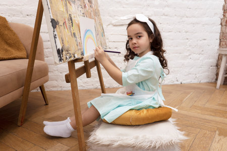 Little girl artist draws rainbow with colored pencils. Drawing lesson in preschool.の写真素材