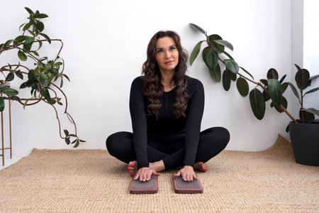 Pretty yogi woman sits in the lotus position and touches a sharp nail on sadhu board.の写真素材