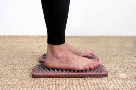 Womans feet standing on wooden sadhu board with sharp nails. Practice of standing on nails.の写真素材
