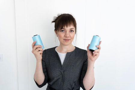 Young seamstress dressmaker keeps two blue spools of thread in hands.の写真素材