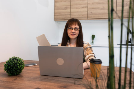 Focused female freelancer accountant with paper glass of coffee checks the documents prepares financial statistics and audit report.の写真素材