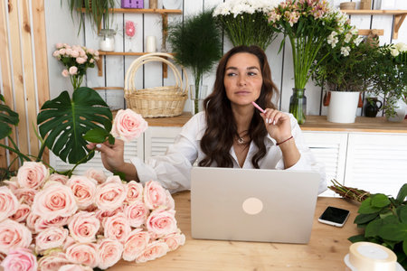 Gorgeous female florist entrepreneur small business owner decides what sort of roses to order for her flower shop.の写真素材